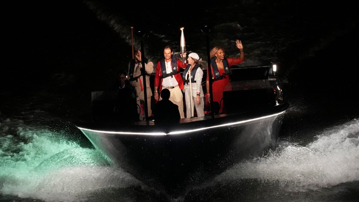 O tenista espanhol Rafael Nadal carrega a tocha olímpica ao lado de outros atletas em um barco pelo Rio Sena - Foto: Christophe Ena/Associated Press/Estadão Conteúdo