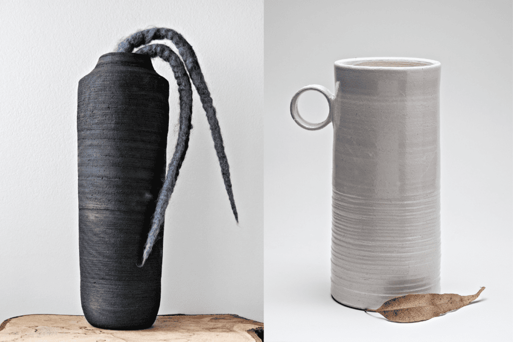Dois vasos de cerâmica, um preto e outro branco, dispostos em um fundo branco