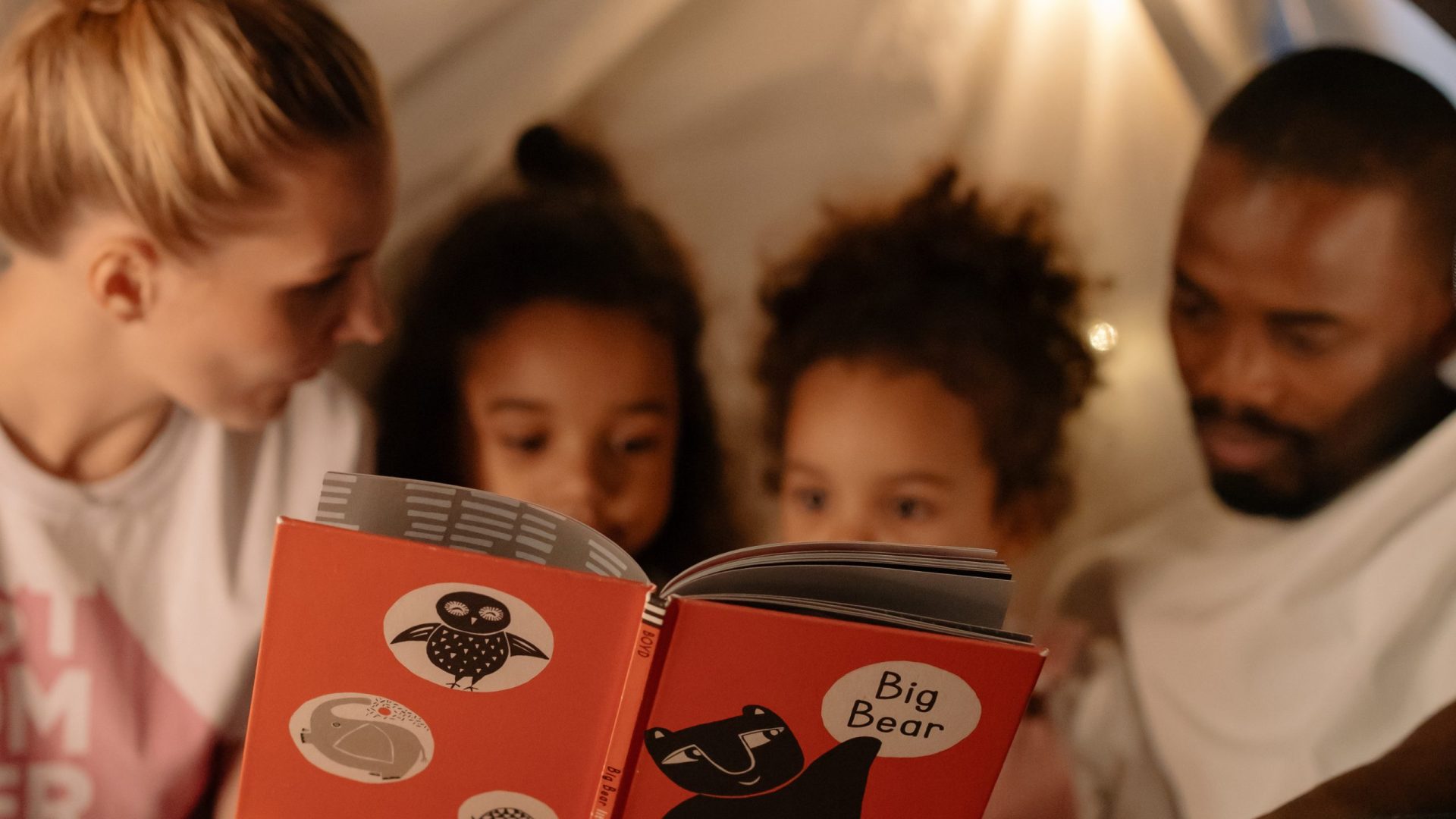 Pais lendo para crianças antes de dormir - Foto: Reprodução/Canva
