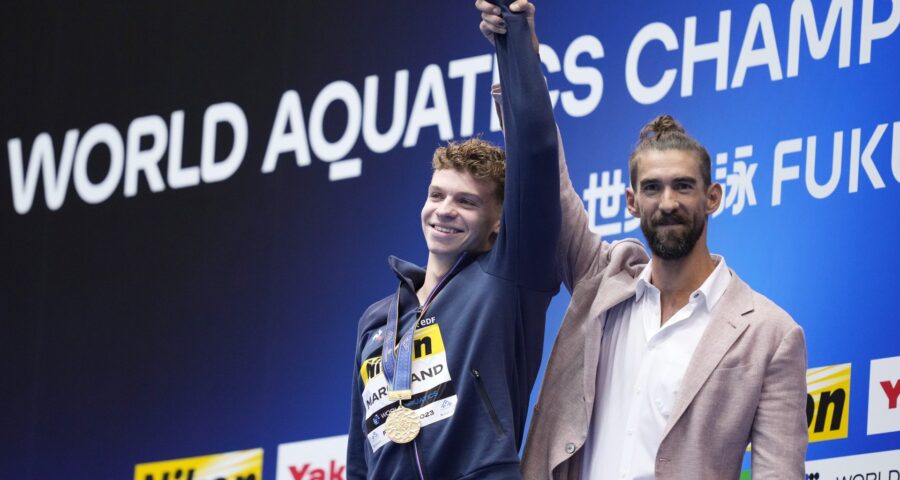 O francês Leon Marchand recebe do ex-nadador americano Michael Phelps a medalha de ouro dos 400m medley da Natação no Mundial de Esportes Aquáticos 2023, em Fukuoka, no Japão - Foto: Eugene Hoshiko/ Associated Press/ Estadão Conteúdo