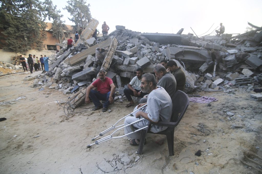Palestinos observam prédio destruído por mais um ataque aéreo israelense em Rafah, Faixa de Gaza, neste sábado (14) - Foto: Hatem Ali/Associated Press/Estadão Conteúdo