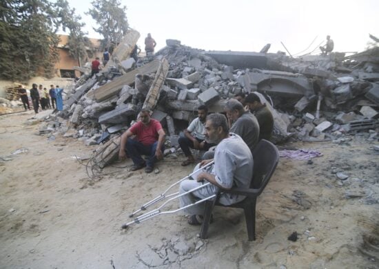 Palestinos observam prédio destruído por mais um ataque aéreo israelense em Rafah, Faixa de Gaza, neste sábado (14) - Foto: Hatem Ali/Associated Press/Estadão Conteúdo