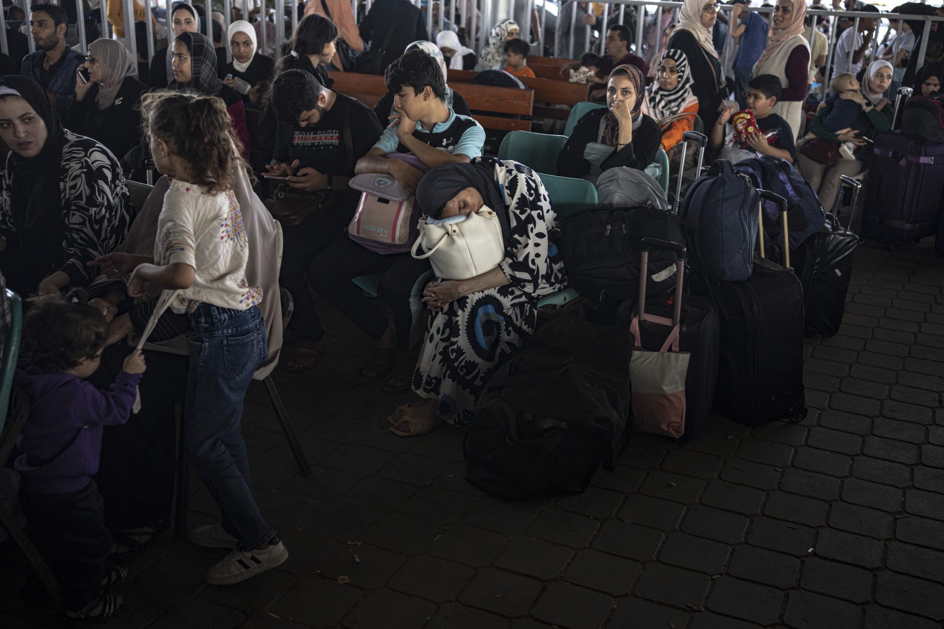 Palestinos e trabalhadores humanitários estrangeiros esperam para cruzar para o Egito em Rafah, na Faixa de Gaza - Foto: Fatima Shabair/ Associeated Press/ Estadão Conteúdo