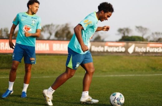 Dois jogadores de uniforme azul e uma bola no campo