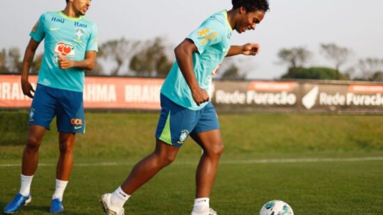 Dois jogadores de uniforme azul e uma bola no campo