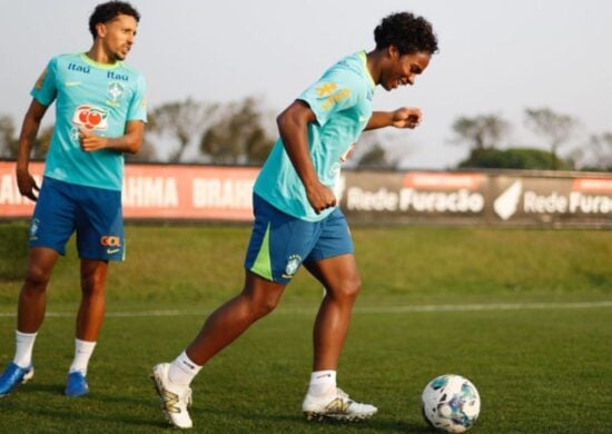 Dois jogadores de uniforme azul e uma bola no campo