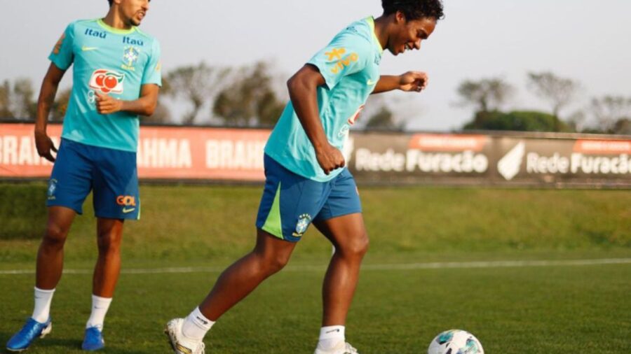 Dois jogadores de uniforme azul e uma bola no campo